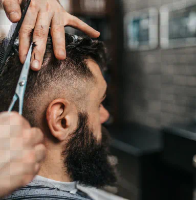 A bearded man gets a haircut.