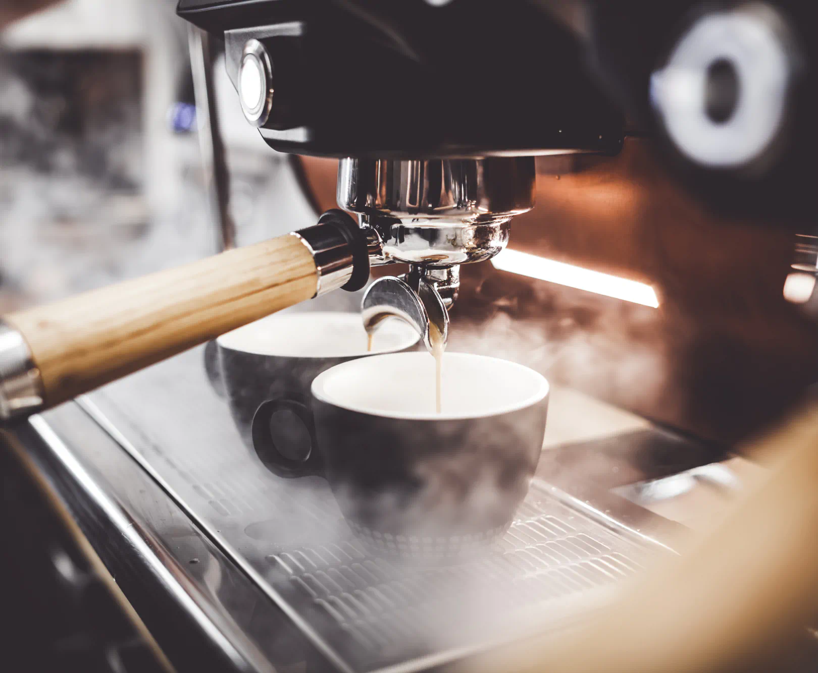 A espresso machine is pouring a shot of espresso surrounded by steam.