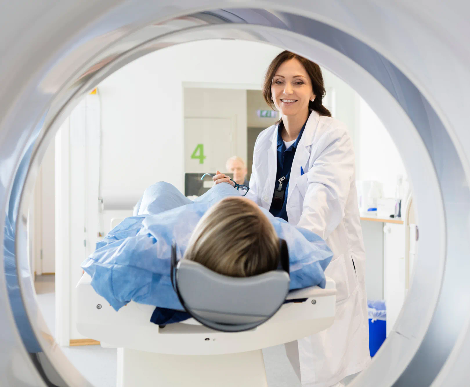 A doctor holds the hand of a patient as they are about to get a c-scan.