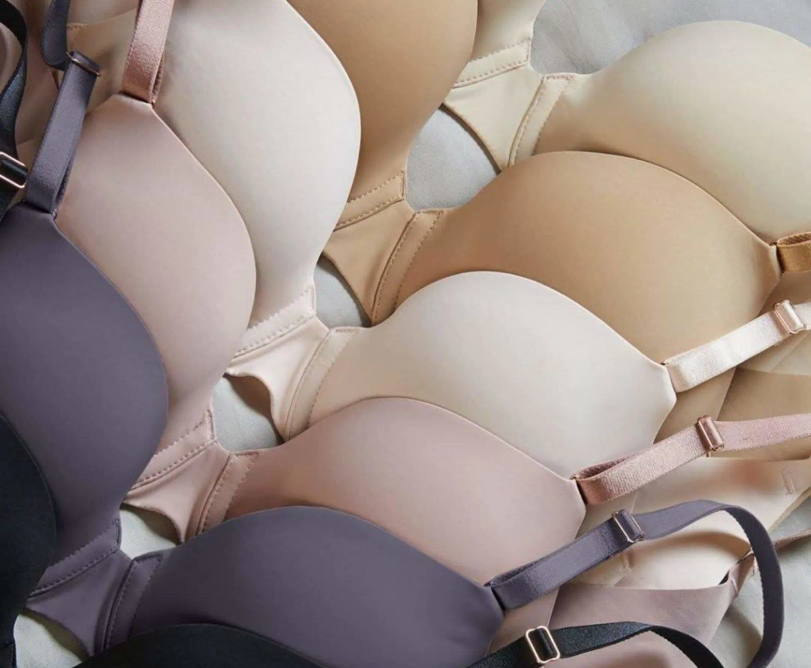 Several bras are strewn across a padded table. The colors range from nude to black.