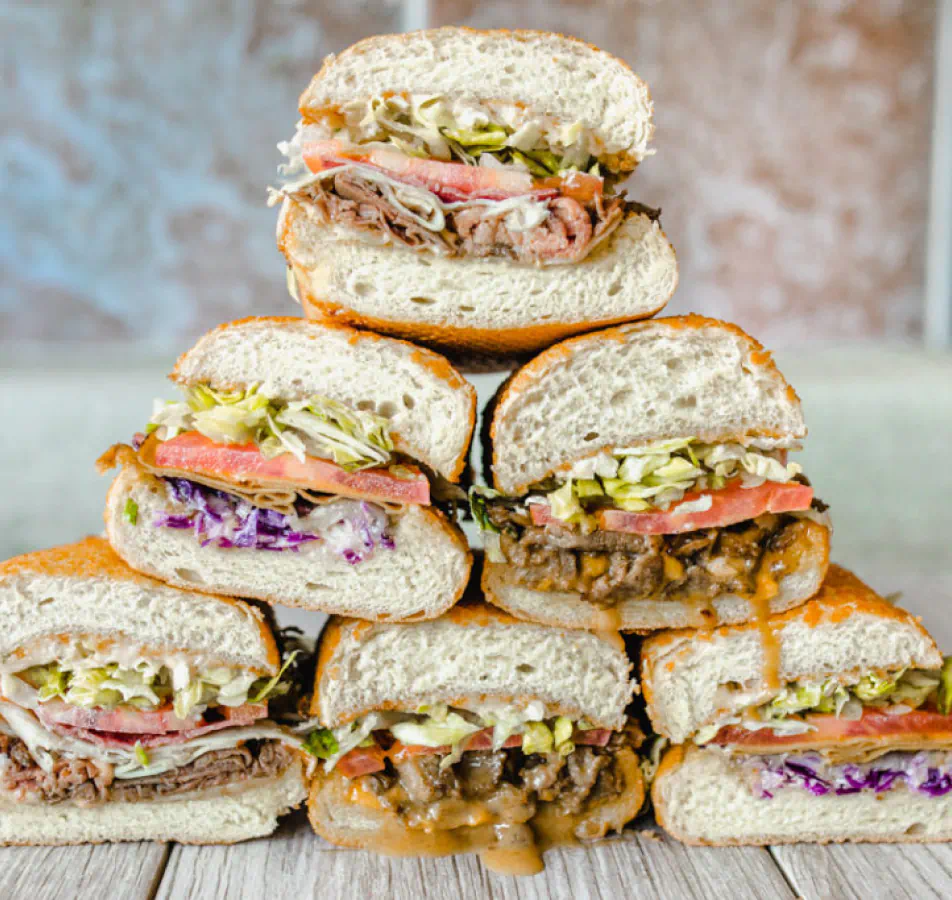 A stack of sub sanwiches in a pyramid shape