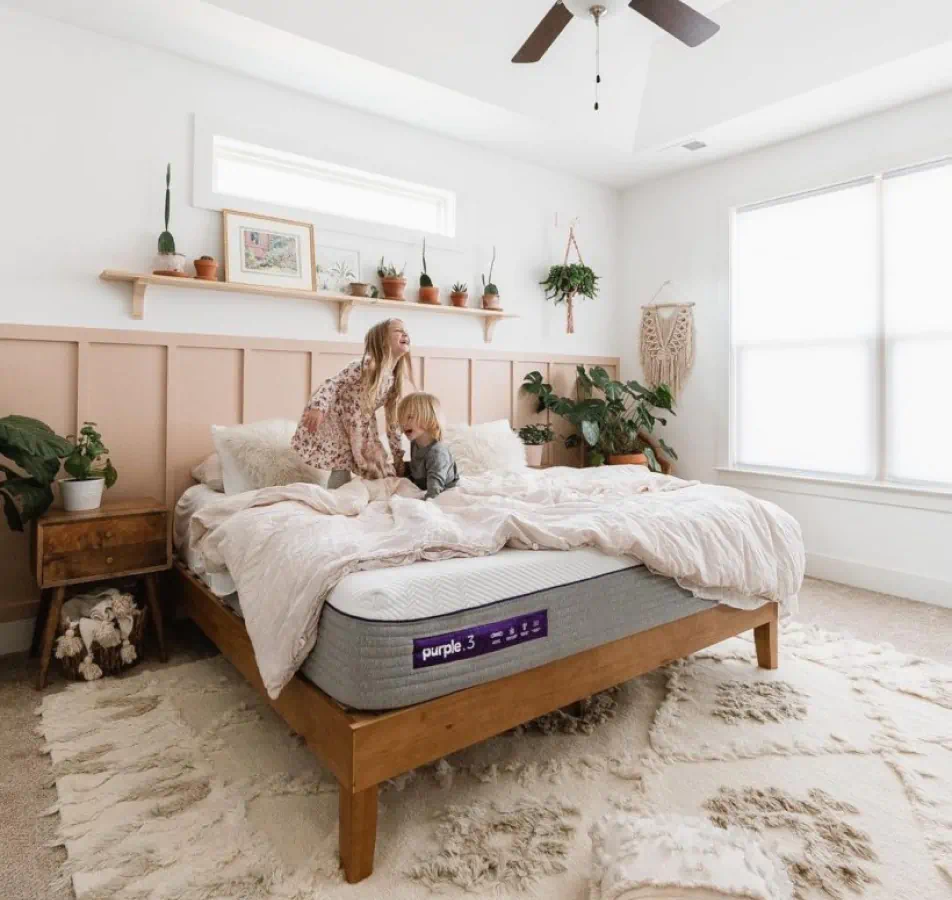 Children sitting on a comfy looking bed