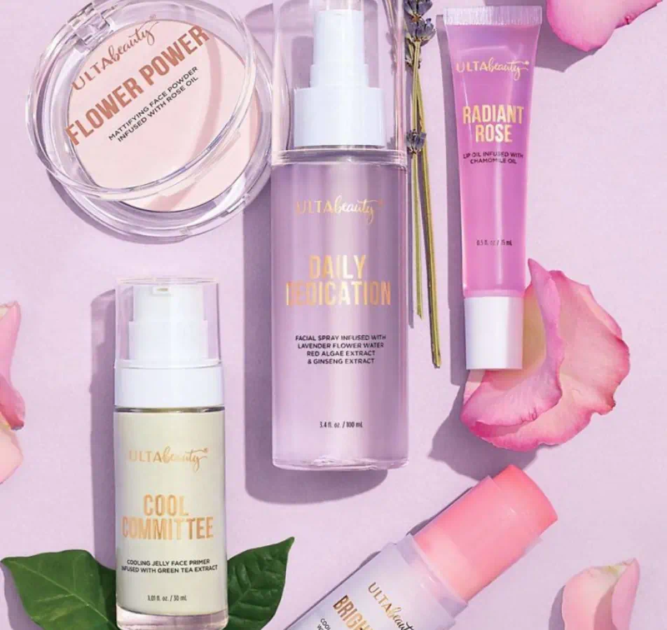 Skin care products organized on pink background with flower