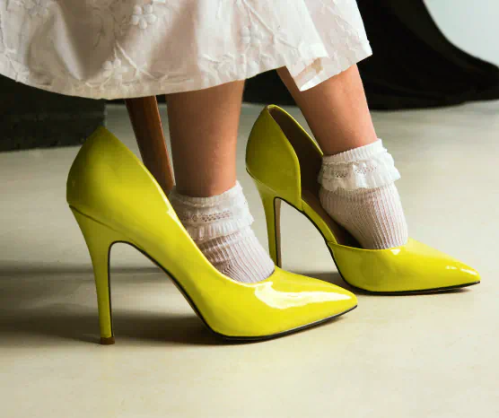 Little girl in a white dress tries on a pair of adult yellow heels