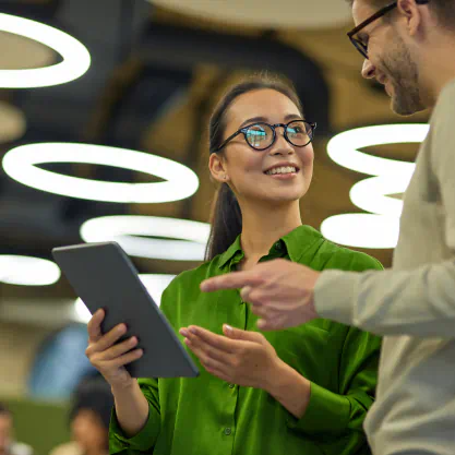 a man and woman wearing business attire discuss something showing on a tablet