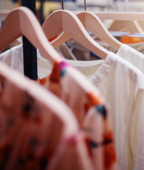 Assorted shirts on wooden hangers.
