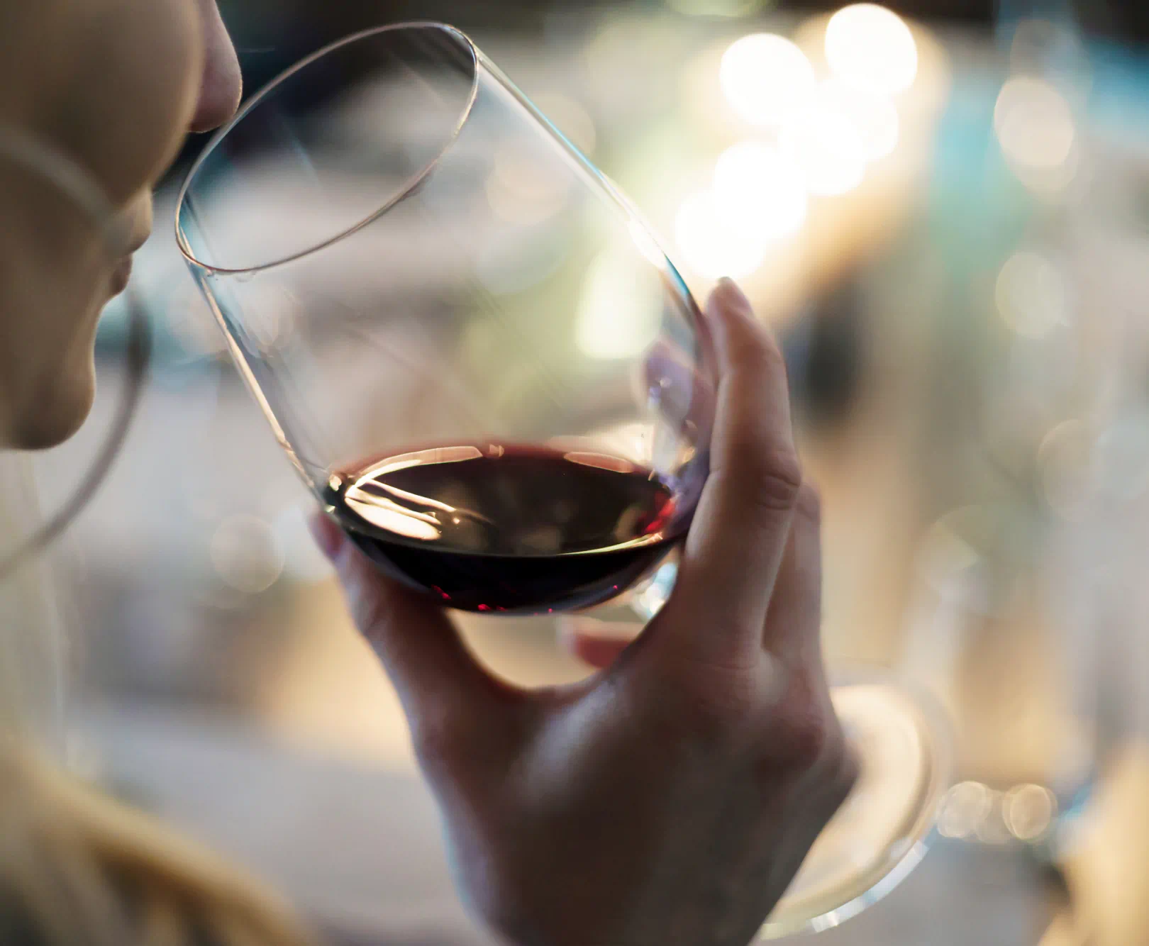 a woman raises a glass of red wine to her mouth