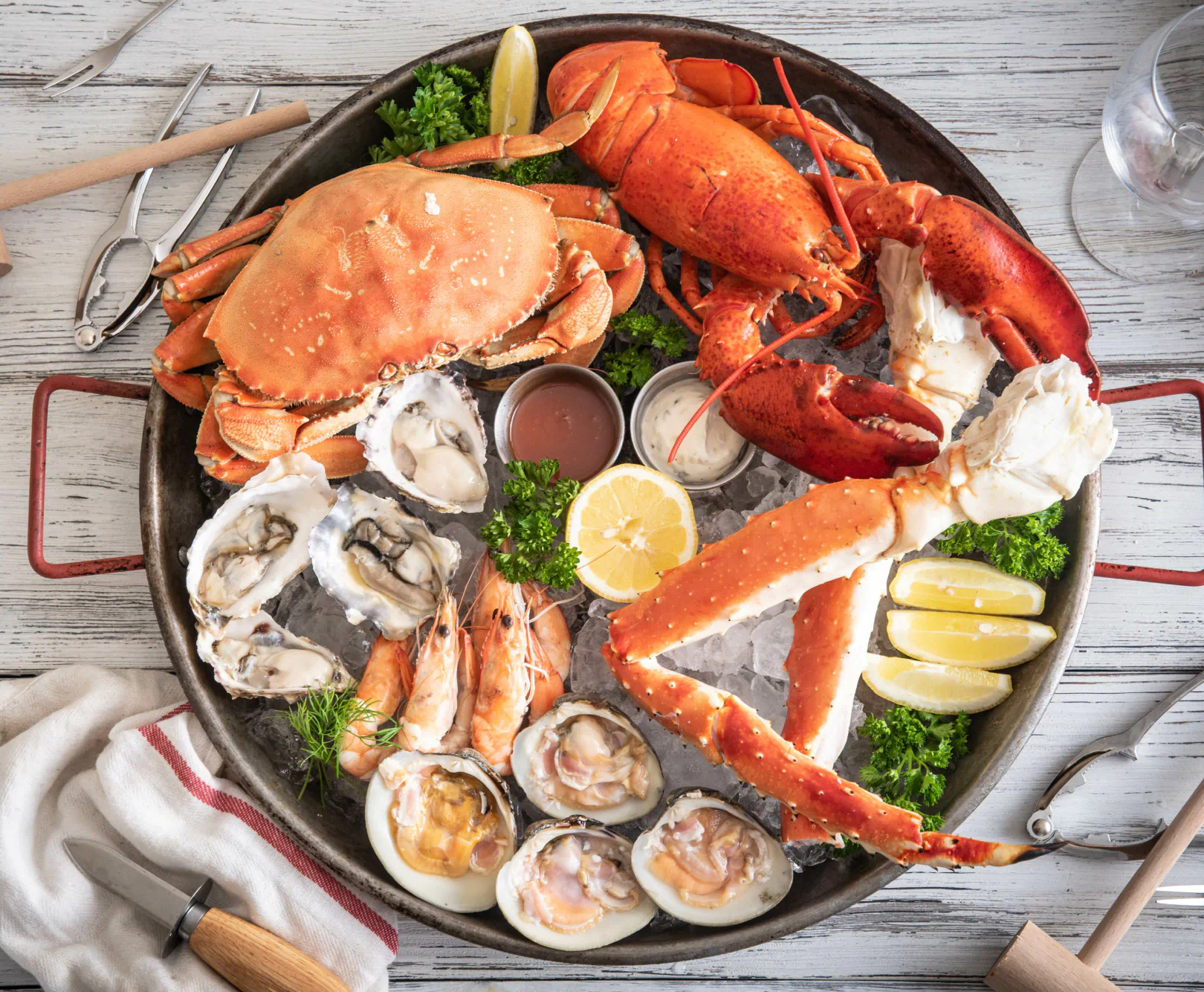 Assorted seafood including crab, lobster, oysters, and shrimp on a large round platter with lemon wedges and parsley.