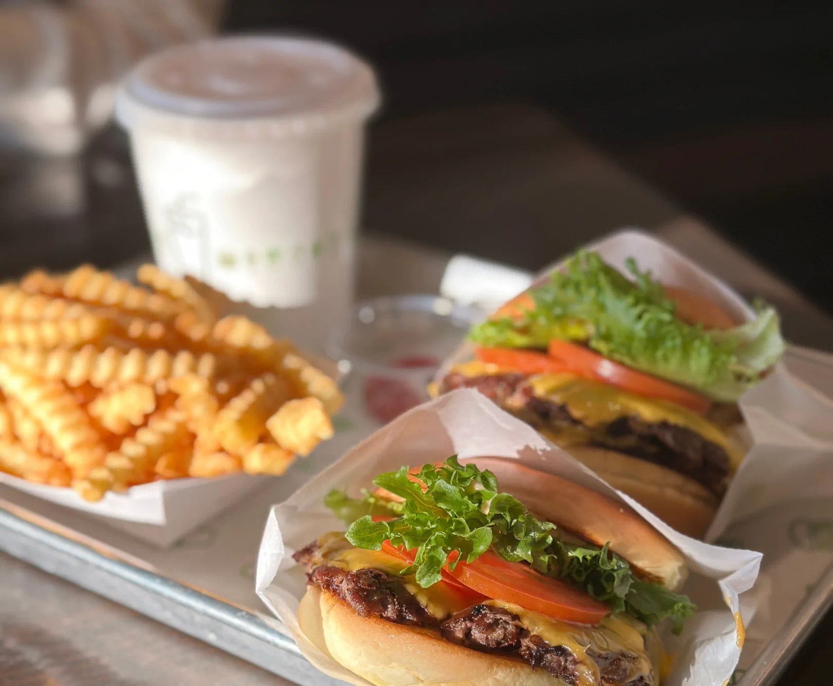 Tray with two cheeseburgers, crinkle-cut fries, and a drink.