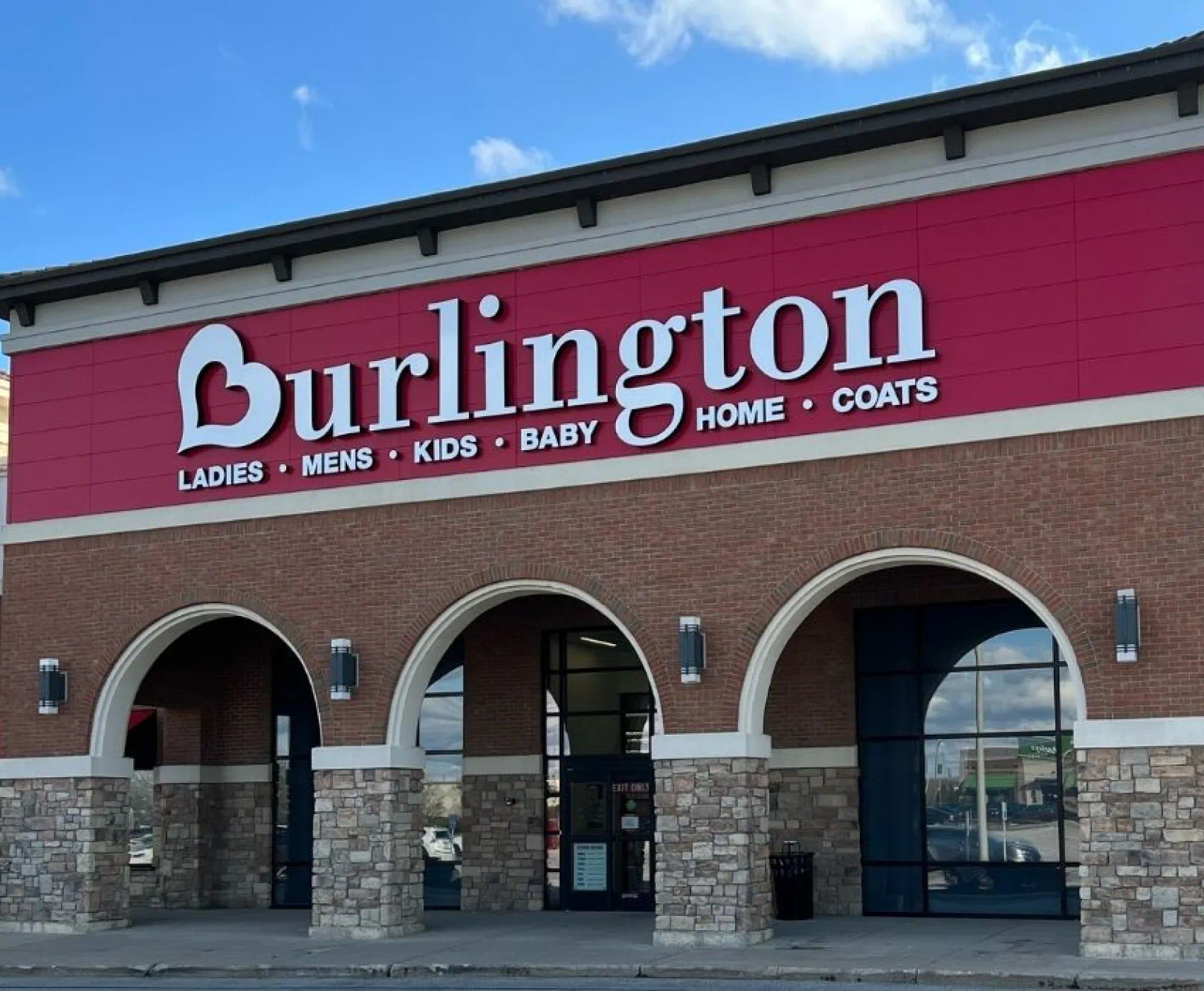 Burlington store exterior with a red sign and white letters, featuring an arched brick and stone entrance.