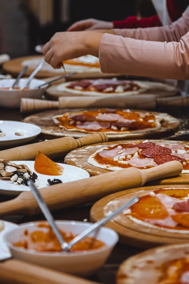 Artisanal pizzas getting made on wood slabs.