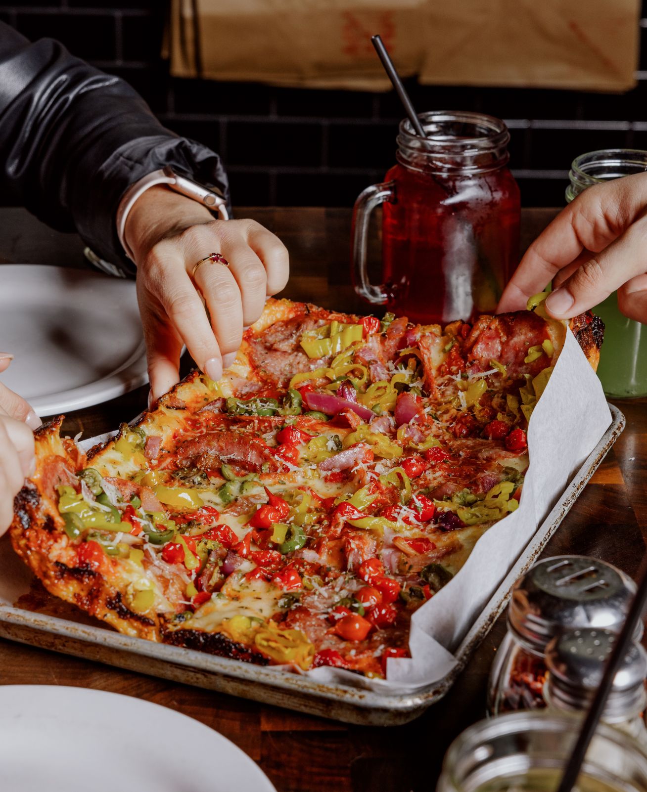 People sharing slices of pizza at a wooden table in a restaurant at Paradise Valley.