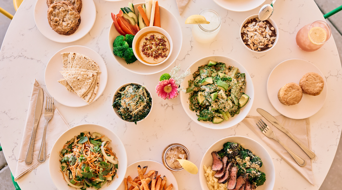 Spread of plated healthy food sitting on a white table.