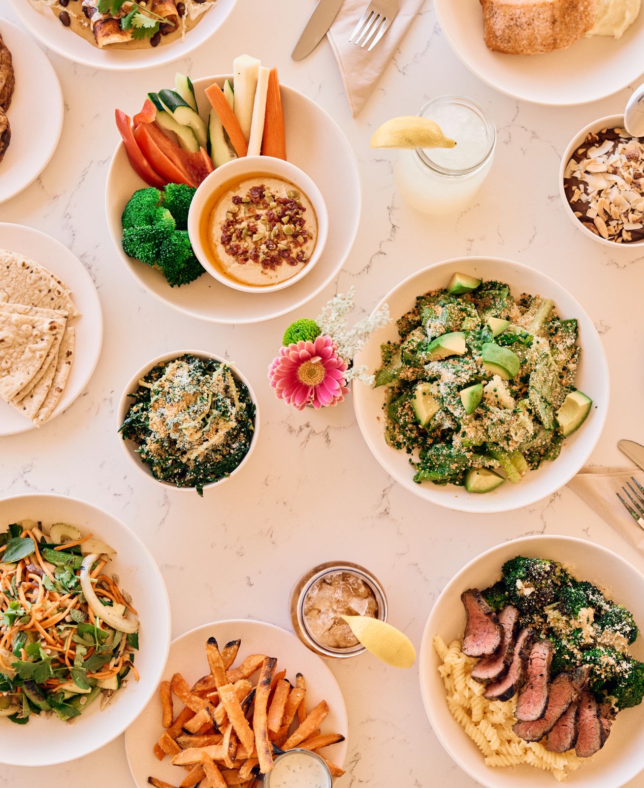 Spread of plated healthy food sitting on a white table.