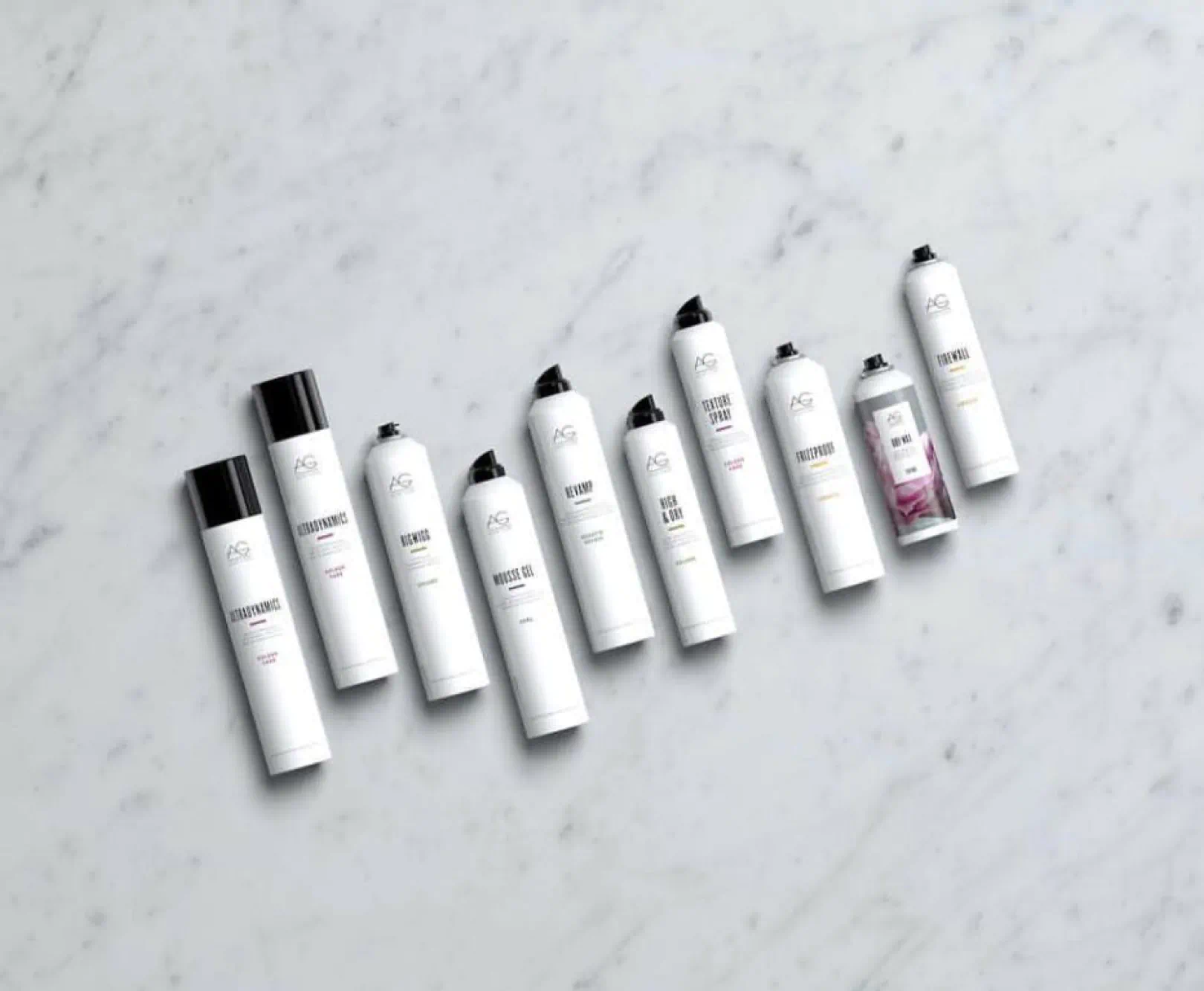 various spray beauty products arranged on a marble surface