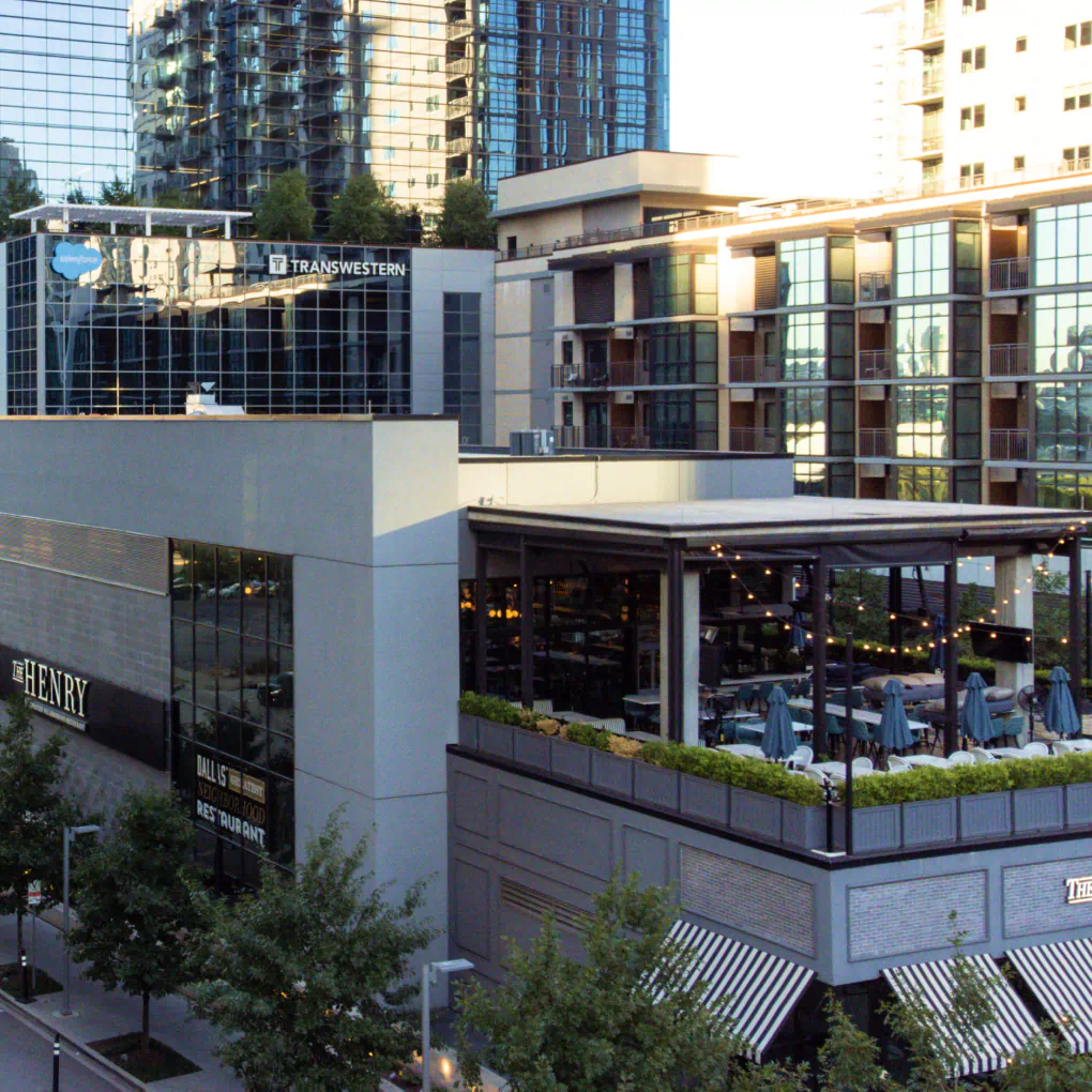 Aerial shot of the restaurant "The Henry", tables line the rooftop bar. Behind the restaurant are tenant buildings and commercial spaces.