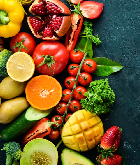 A collection of vibrant fruits and vegetables sit on a green table.