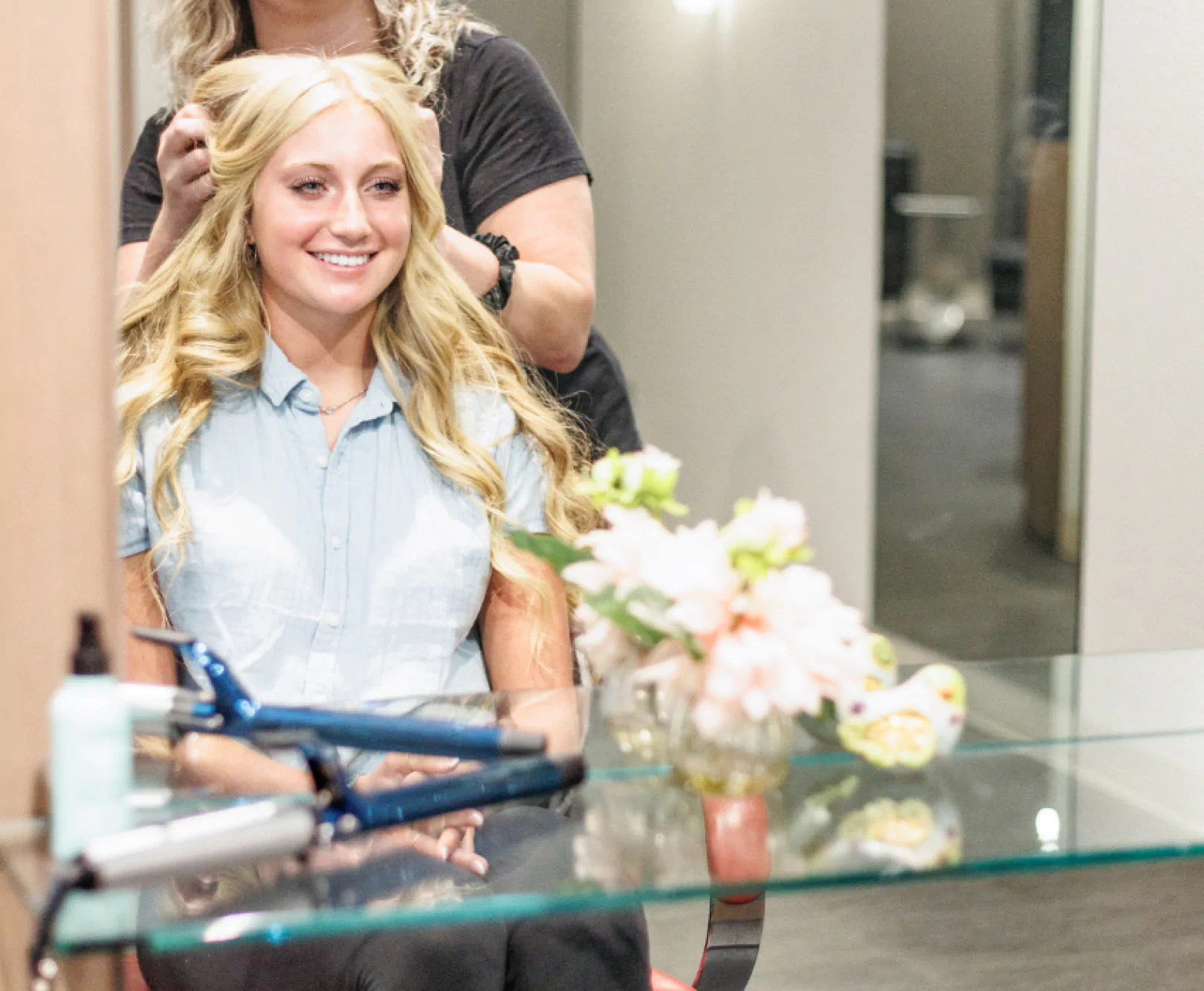 A stylist adds volume to a customers shiny blond hair.
