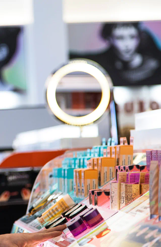A cosmetic ring light shines brightly over a large display stand showcasing several containers of makeup.