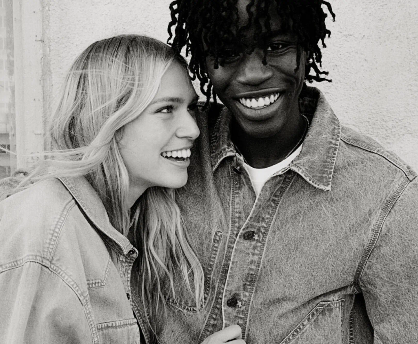 A couple smiles from the camera as they show off their denim coats.