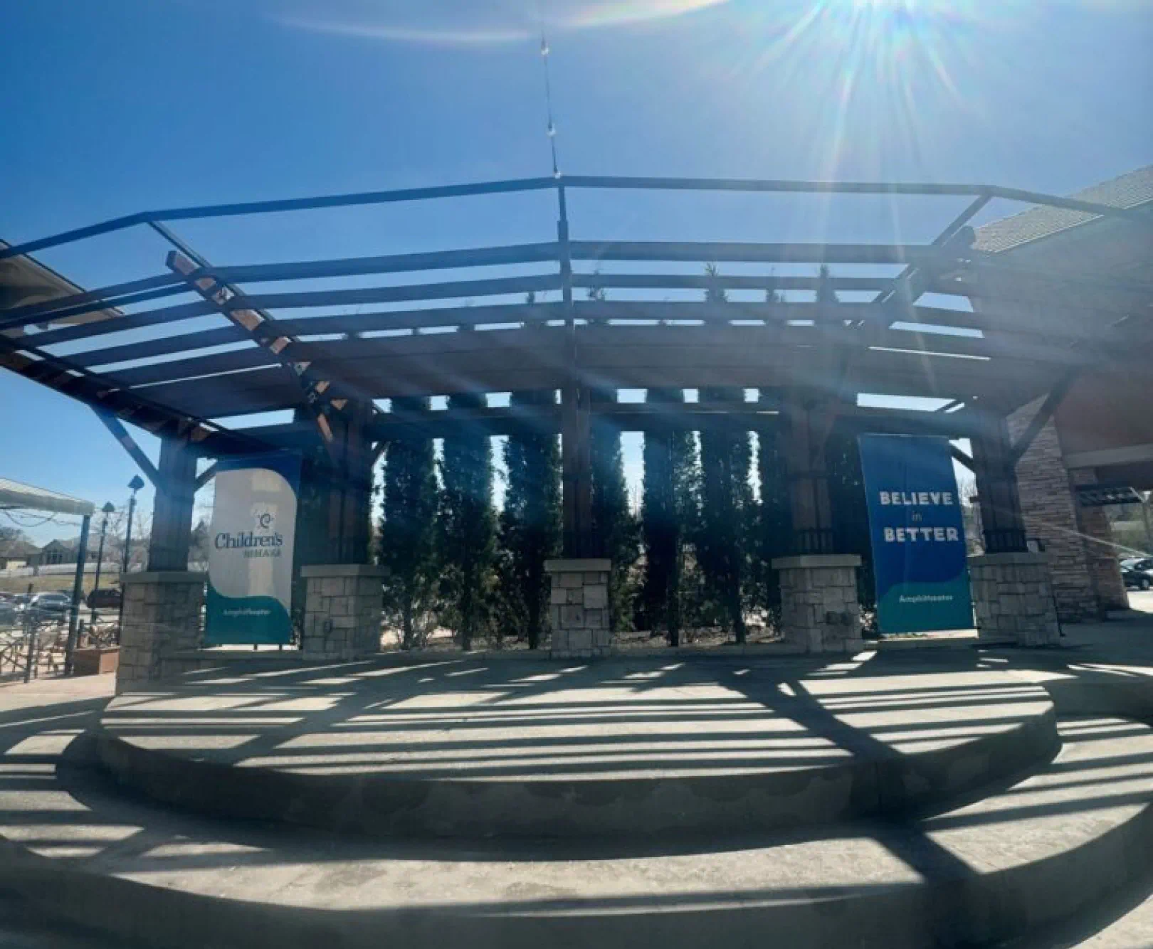 The sun shines down on the Village Pointe amphitheater. Two sign sit stage left and right showing various tenets.