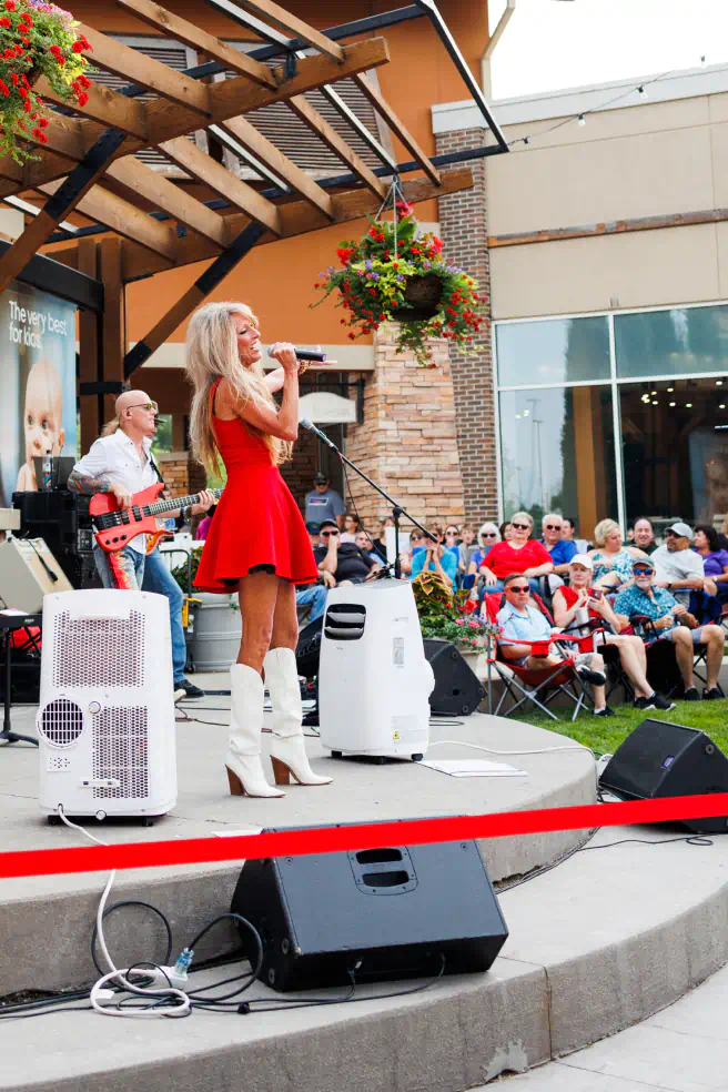 Singer in a dress and cowboy boots on an outdoor stage at Village Pointe.